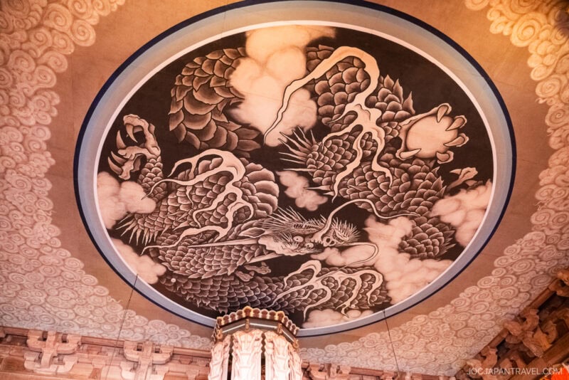 Circular ceiling mural of a dragon surrounded by clouds, painted in black and white with intricate details and scales, located inside the historic Kenchoji Temple, a traditional Japanese building.