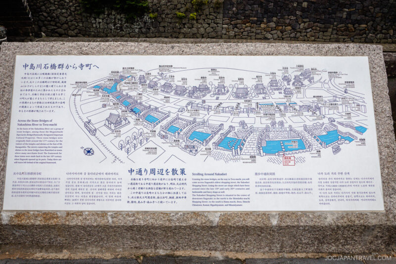 A detailed illustrated map with Japanese and English text shows historic sites, landmarks, and buildings along Nakabashi Bridge and the Nakashima River in Takayama, Japan. Blue highlights indicate notable locations, with descriptions for each site.