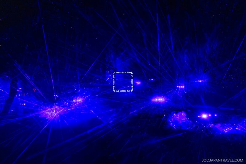 A vibrant display of deep blue laser lights beams through a dark space, evoking the futuristic atmosphere of Lake Kussharo at night, with illuminated patterns and reflections shimmering like mist over the water.