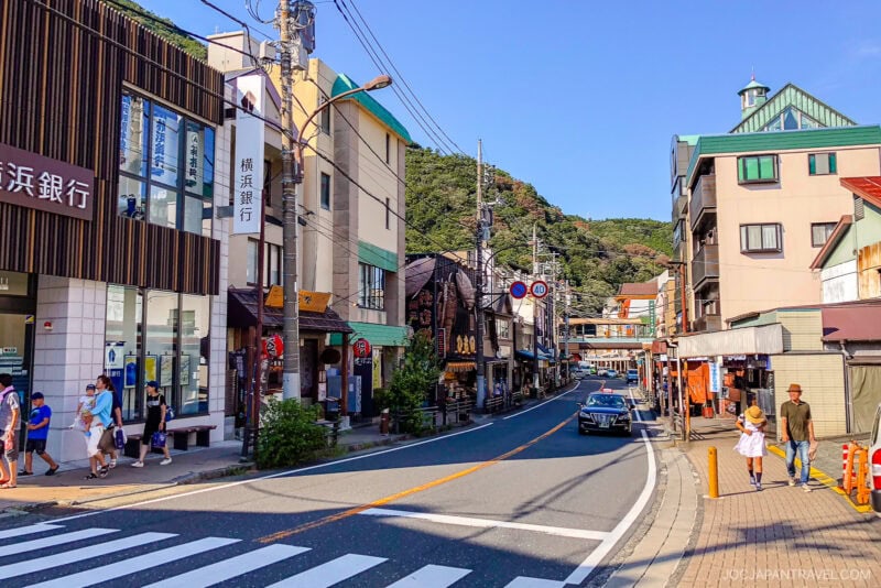 A street in hakone-yumoto with buildings and cars on it.