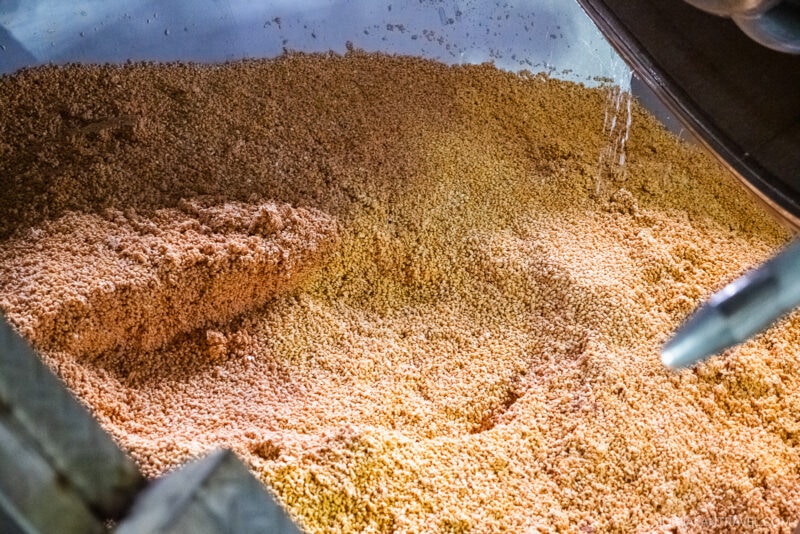 A close-up view of wet, crushed grains inside a metal brewing vessel, reminiscent of mash used in beer production—similar to scenes you might spot on a Hikari Miso factory tour.