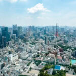 Tokyo City View & Mori Art Museum – Views and Culture at Mori Tower Aerial view of Tokyo’s cityscape with dense high-rise buildings, the iconic Tokyo Tower in the distance, and a hazy sky overhead captures a stunning tokyo city view.
