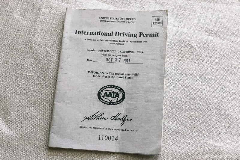 A U.S. International Driving Permit booklet, perfect as a Japan driving guide, issued in Foster City, California on October 27, 2017, with a $20 fee stamp and an official signature, resting on a textured white surface.