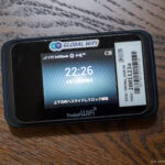 The Ultimate Guide to Japan Wifi A Japan Wifi portable device rests on a wooden surface, displaying the time 22:26 on its screen with LTE SoftBank signal indicators and a barcode sticker on the top right corner.