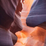 Lower Antelope Canyon – A Family Guide to Arizona’s Famous Slot Canyon Sunlight streams through the smooth, swirling orange and purple sandstone walls of Lower Antelope Canyon, highlighting the layered textures and curves of this stunning slot canyon.