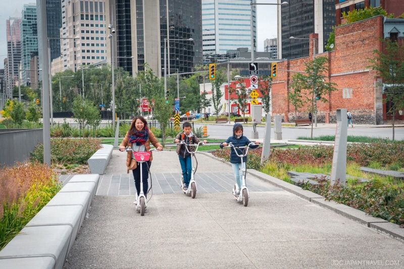 A woman and a child riding scooters on a sidewalk in Montreal.