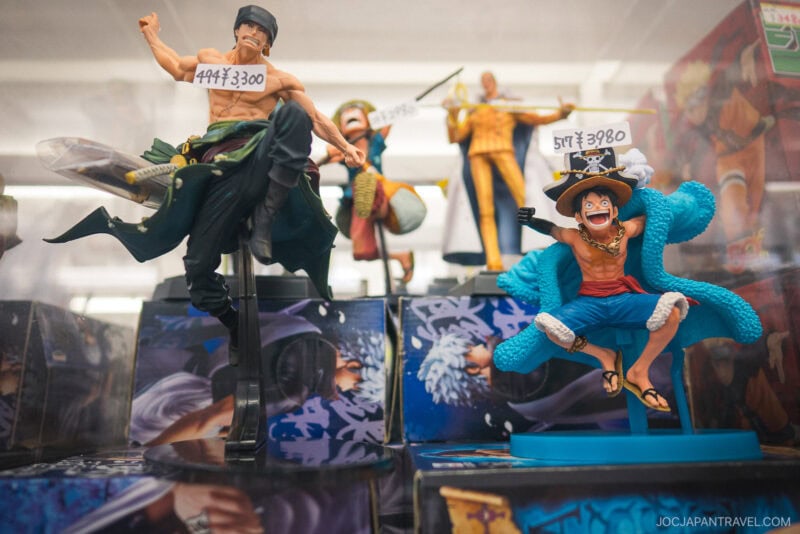 Two One Piece anime character figurines are displayed in a shop, each with a yen price tag on their heads&mdash;a common sight in Akihabara Hobby Stores, where shelves are filled with more anime figures and merchandise.