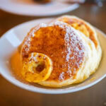 Bills Odaiba at DECKS Tokyo Beach: Dining with a Bay View A plate of fluffy pancakes dusted with powdered sugar and garnished with banana, served on a white dish at Bills Odaiba at DECKS.