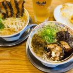 Daruma Ramen (博多だるま) – Authentic Hakata-Style Tonkotsu Ramen in Fukuoka Two bowls of Daruma Ramen Fukuoka with sliced pork, green onions, and various toppings sit on a wooden table, accompanied by a plate of gyoza and a glass of Asahi beer in the background.