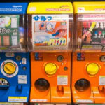 Akihabara Gachapon Hall (秋葉原ガチャポン会館) – Tokyo’s Ultimate Capsule Toy Wonderland Three colorful Japanese capsule toy vending machines from Akihabara Gachapon Hall, each labeled in Japanese and displaying images of collectible toys like pouches, pens, and figurines.