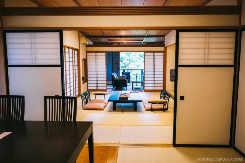 A traditional Japanese tatami room with low wooden tables, floor cushions, sliding shoji doors, and garden views—an inviting glimpse of where to stay in Japan for an authentic cultural experience.
