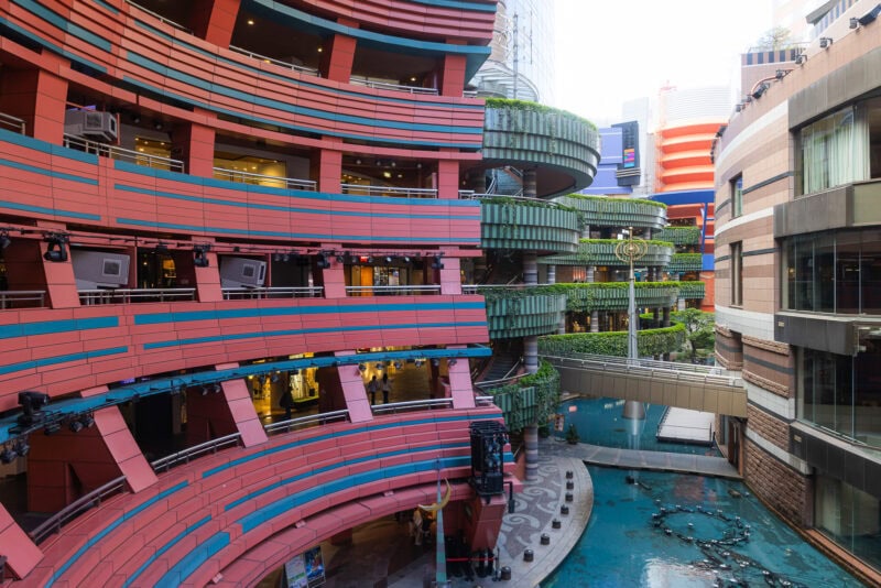 A modern, colorful multi-level shopping complex, Canal City Hakata features curved red and green balconies, glass railings, and a blue water feature below&mdash;an iconic Fukuoka entertainment complex surrounded by tall buildings.